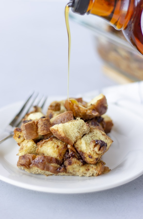 Maple syrup being poured onto a plate of french toast.