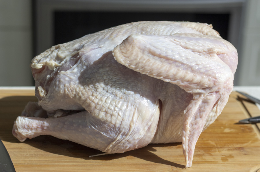 Whole raw turkey on a wood cutting board.