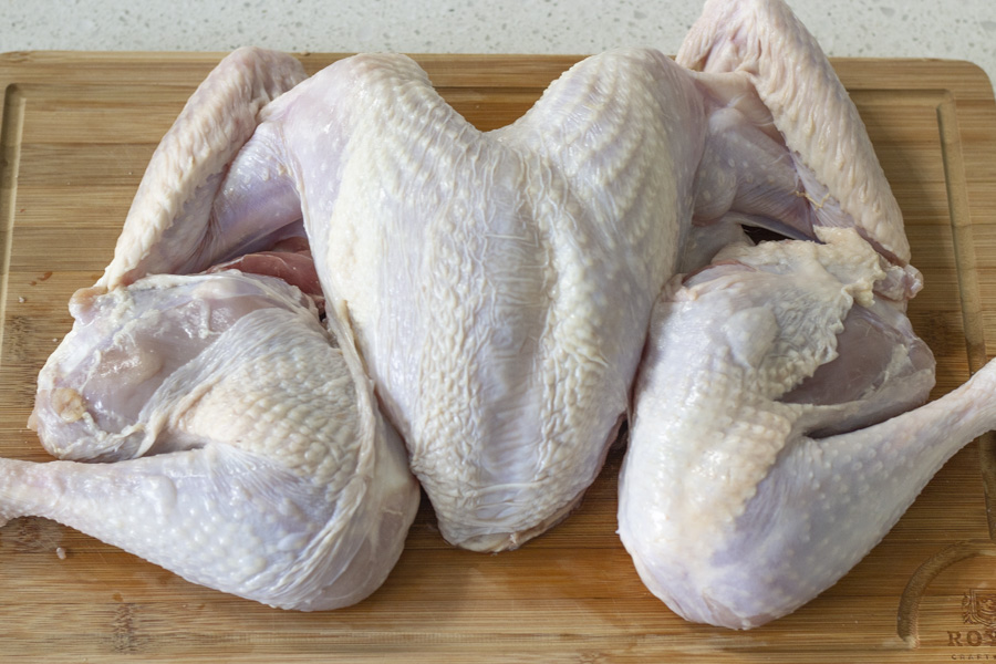 Spatchcocked raw turkey on a wood cutting board.