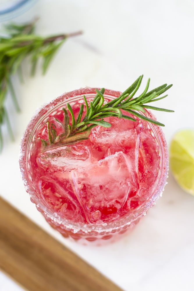 Overhead view of elderberry margarita with a sprig of rosemary in the drink.