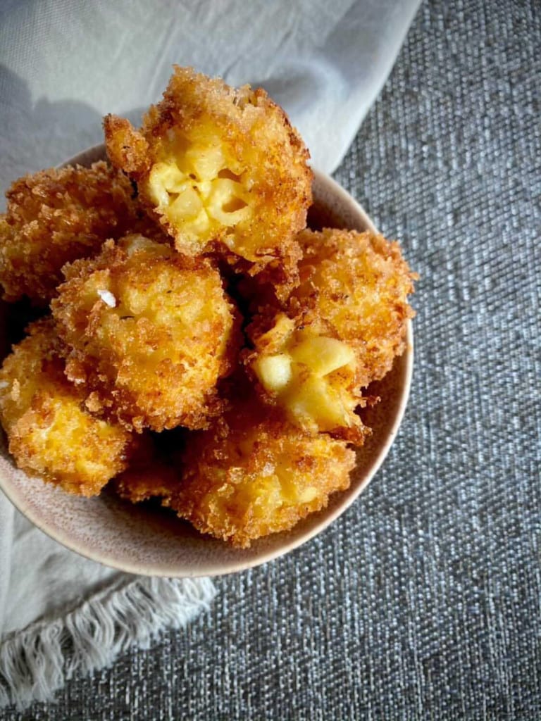 Fried Mac and Cheese Bites in a small bowl under a grey cloth.