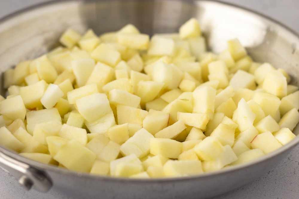 Diced raw apples inside a skillet.