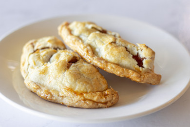 Two baked apple empanadas on a white plate.