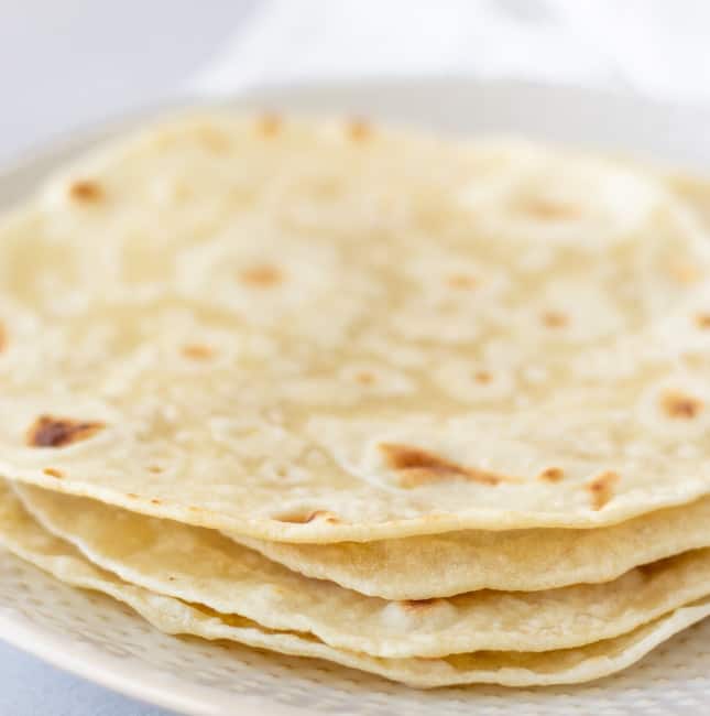 Stack of tortillas on a white plate