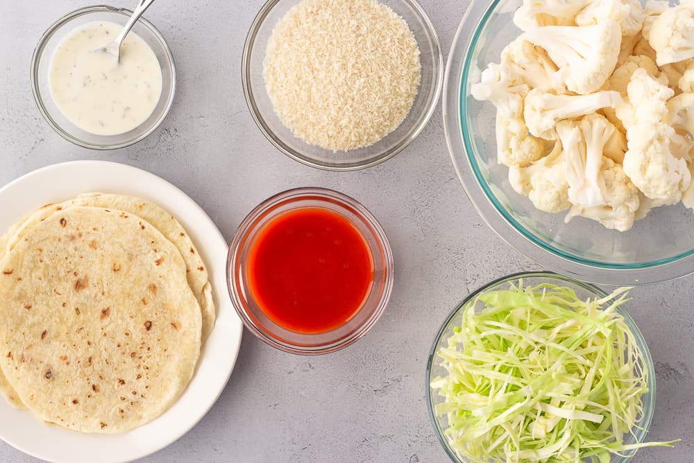 overhead view of ingredients, cauliflower, buffalo sauce, panko, cabbage, and tortillas.