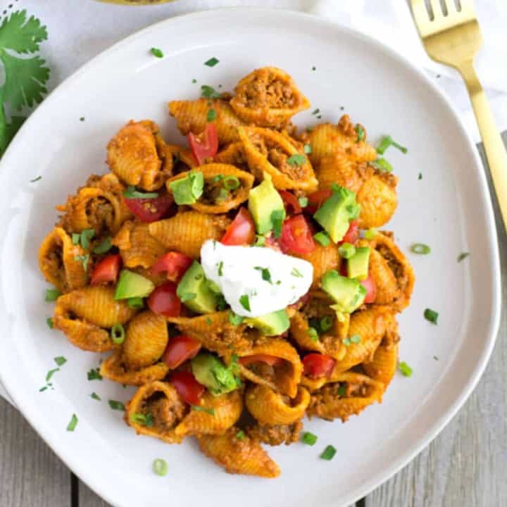 Overhead view of taco pasta on a white plate with a gold fork on the side.