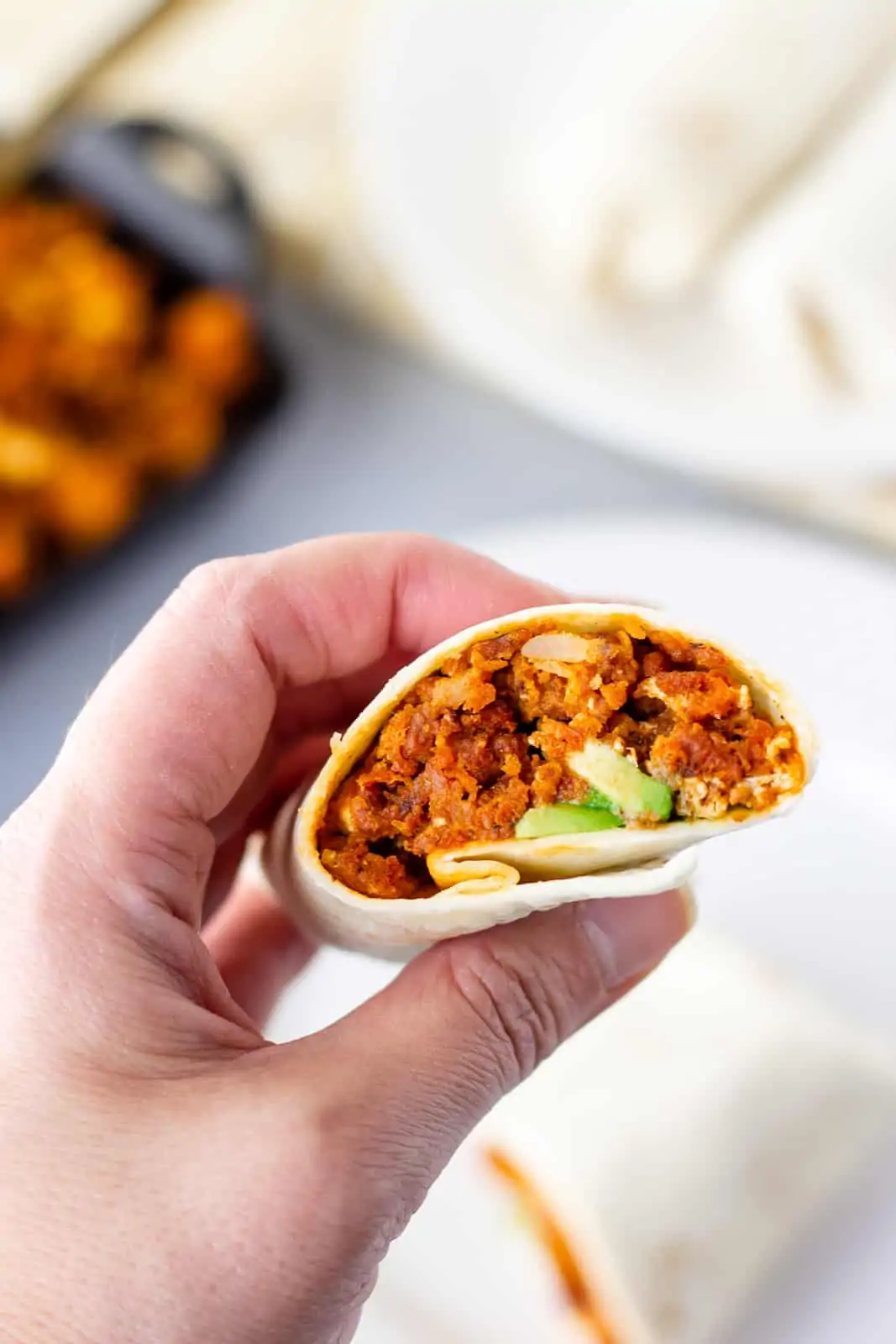 Hand holding half of a burrito showing the chorizo potato and egg filling.