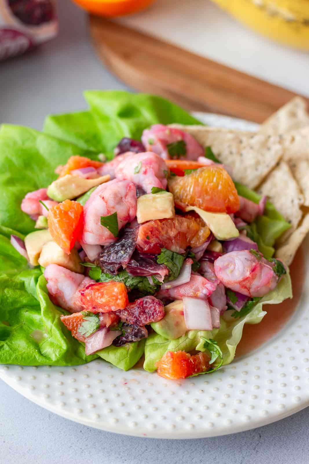 Up close view of shrimp ceviche on a plate with tortilla chips on a bed of lettuce.