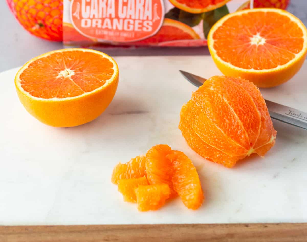 Cara Cara orange cut in half and one diced on a marble cutting board.