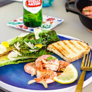 Blue plate with grilled shrimp, grilled romaine, and a slice of bread.