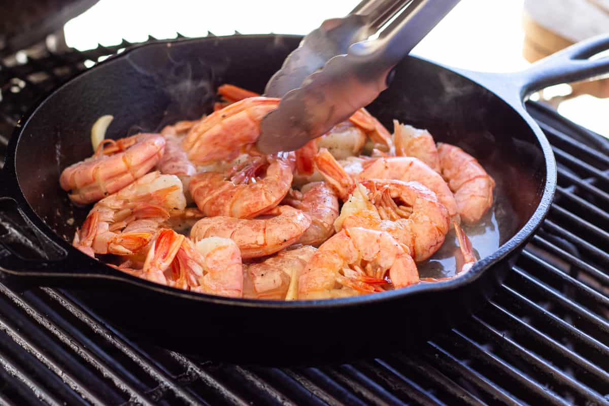 Shrimp cooking on the grill in a cast iron skillet.