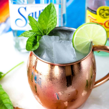 Mexican mule cocktail in a copper mug with condensation on the side and a mint and lime slice garnish.