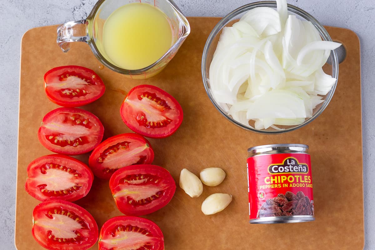 Halved tomatoes, garlic, onions, broth, and a can of chipotles.