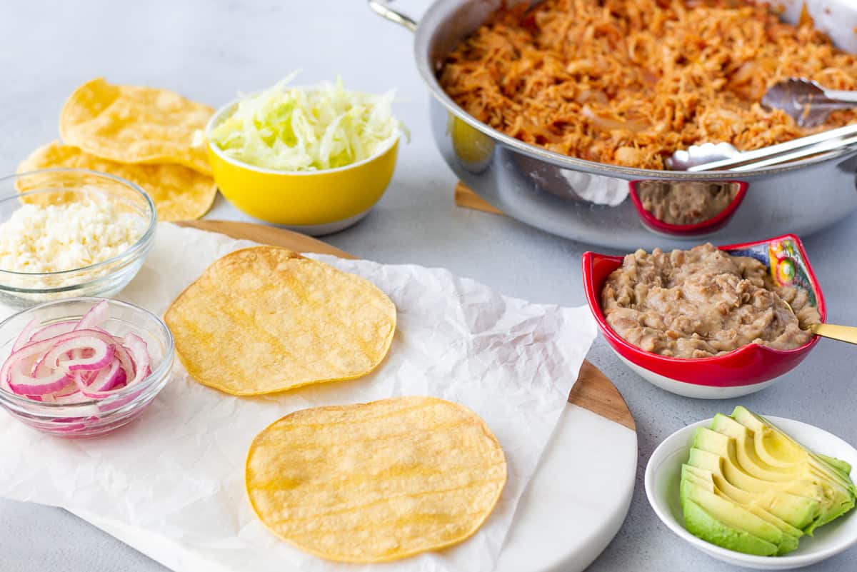 Ingredients in separate bowls with tostadas on a board.