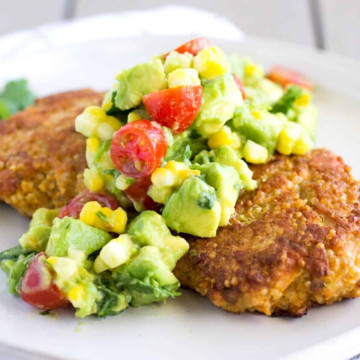 Two salmon patties topped with avocado corn salsa.