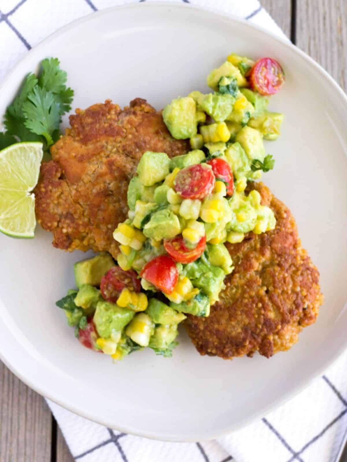 Overhead view of salmon patties on a white plate with cilantro and lime garnish.