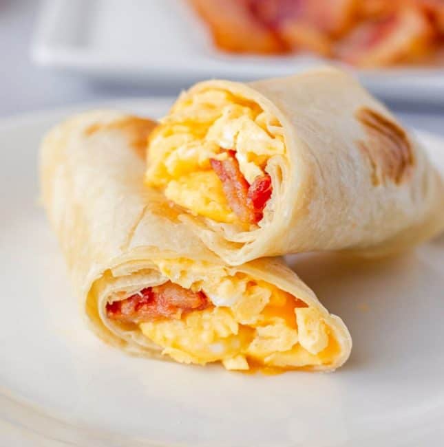 Feature image of bacon egg and cheese burrito sliced in half stacked on a plate.