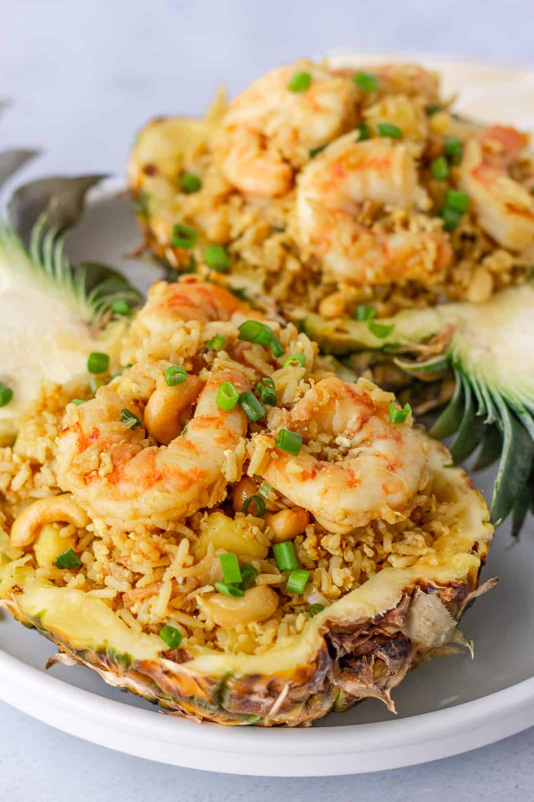 Two pineapple shells with fried rice on a white plate.