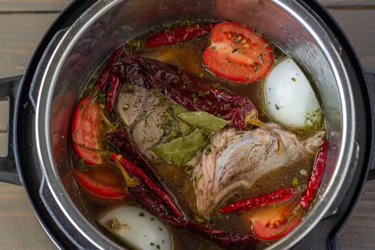 Ingredients in Instant Pot (peppers, tomatoes, onion, oregano, and beef shanks.)