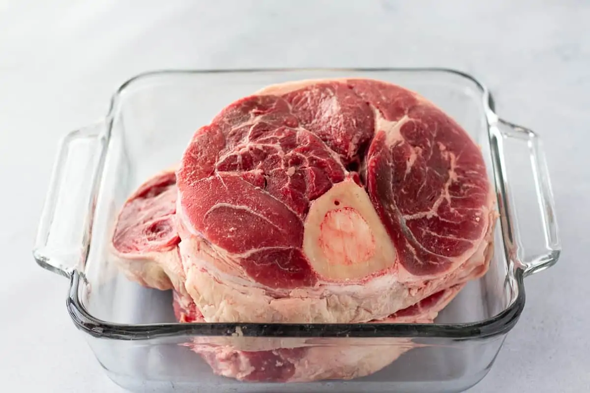 Uncooked pieces of beef shanks in a glass dish.