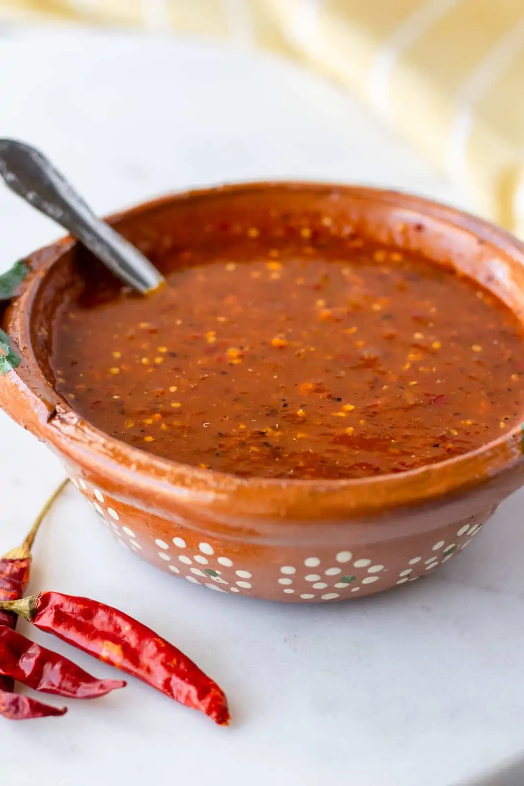 Up close view of salsa in a clay bowl on a marble board.