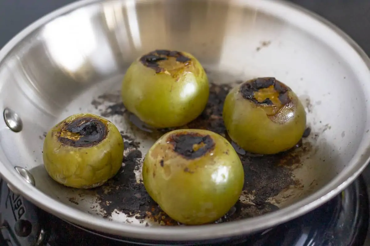 Tomatillos roasting on a pan.
