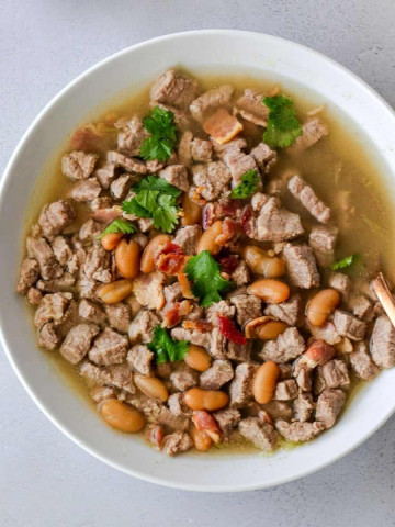 Overhead view of beef soup in a white bowl.
