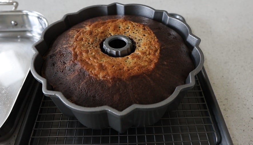 Baked chocoflan in the bundt pan, cooling on a baking rack.