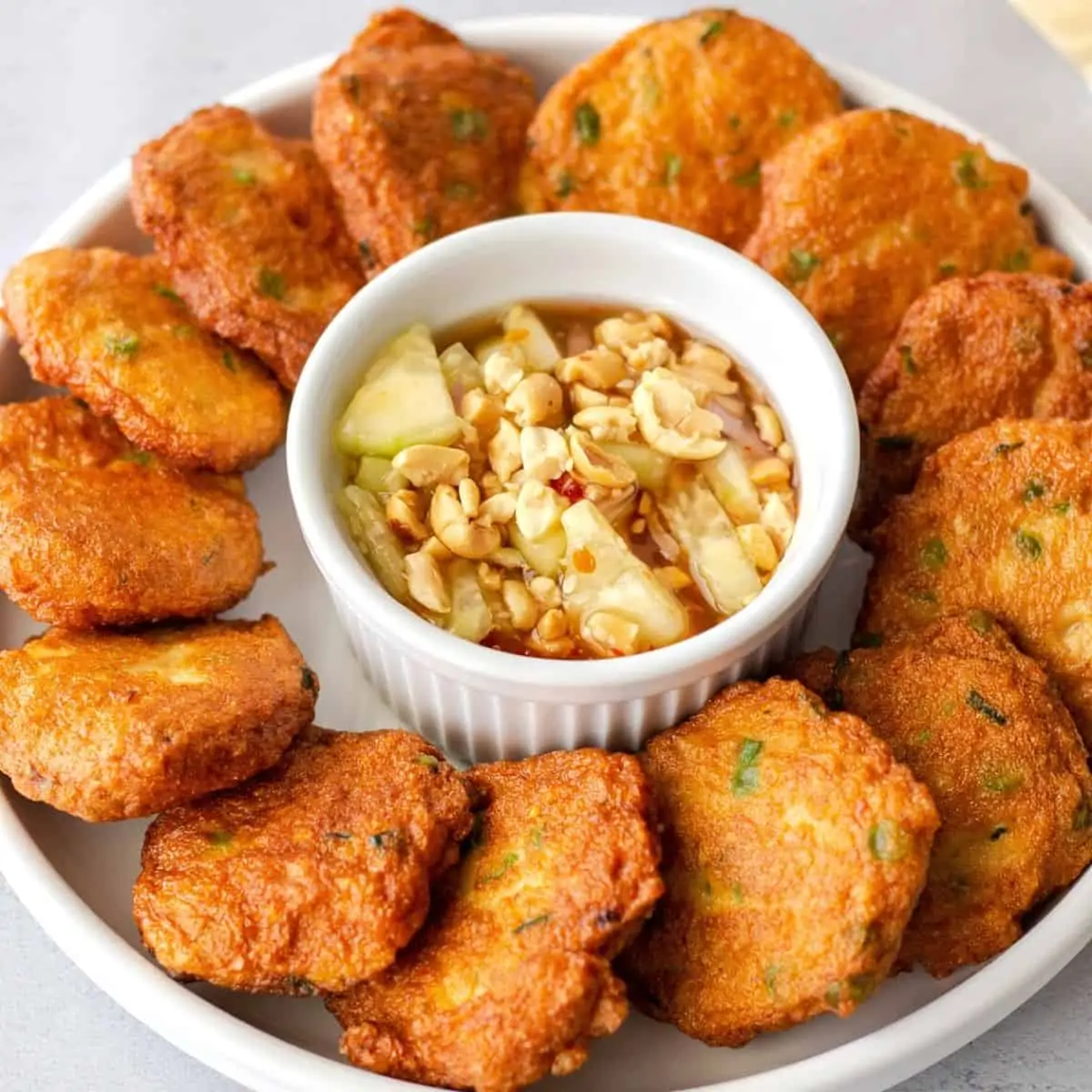 Cooked fish cake on a round plate with dipping sauce in the middle.