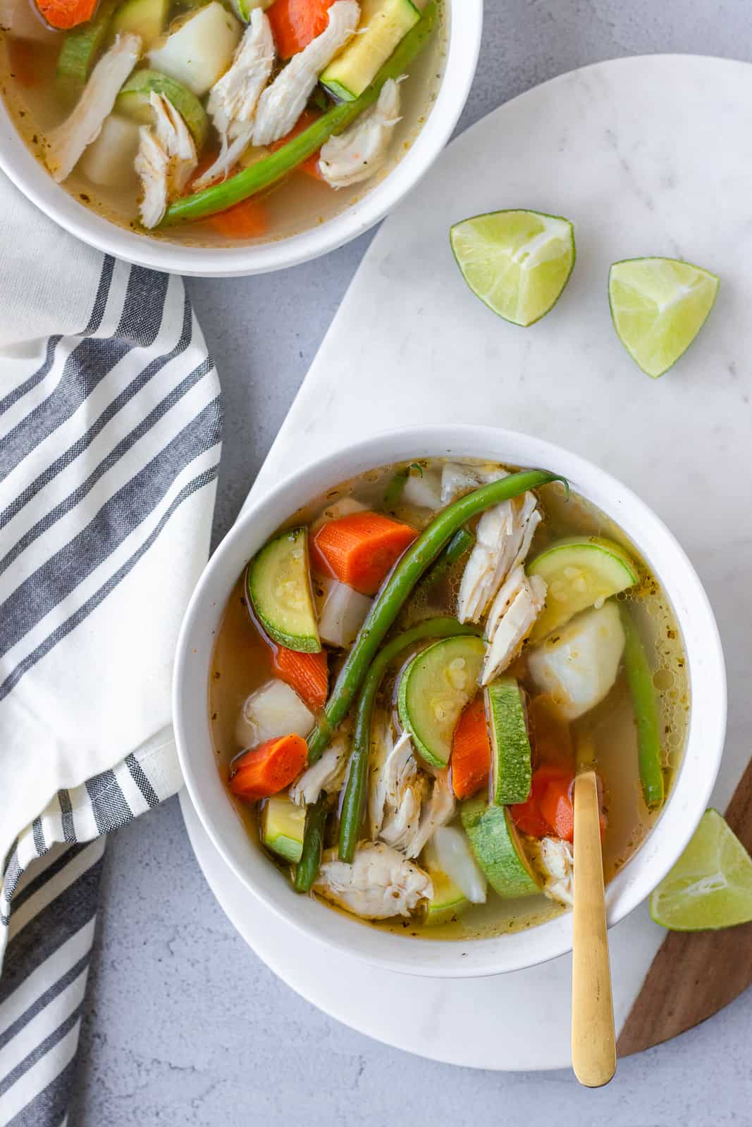 Overhead view of 2 bowls of soup and lime wedges on the side.