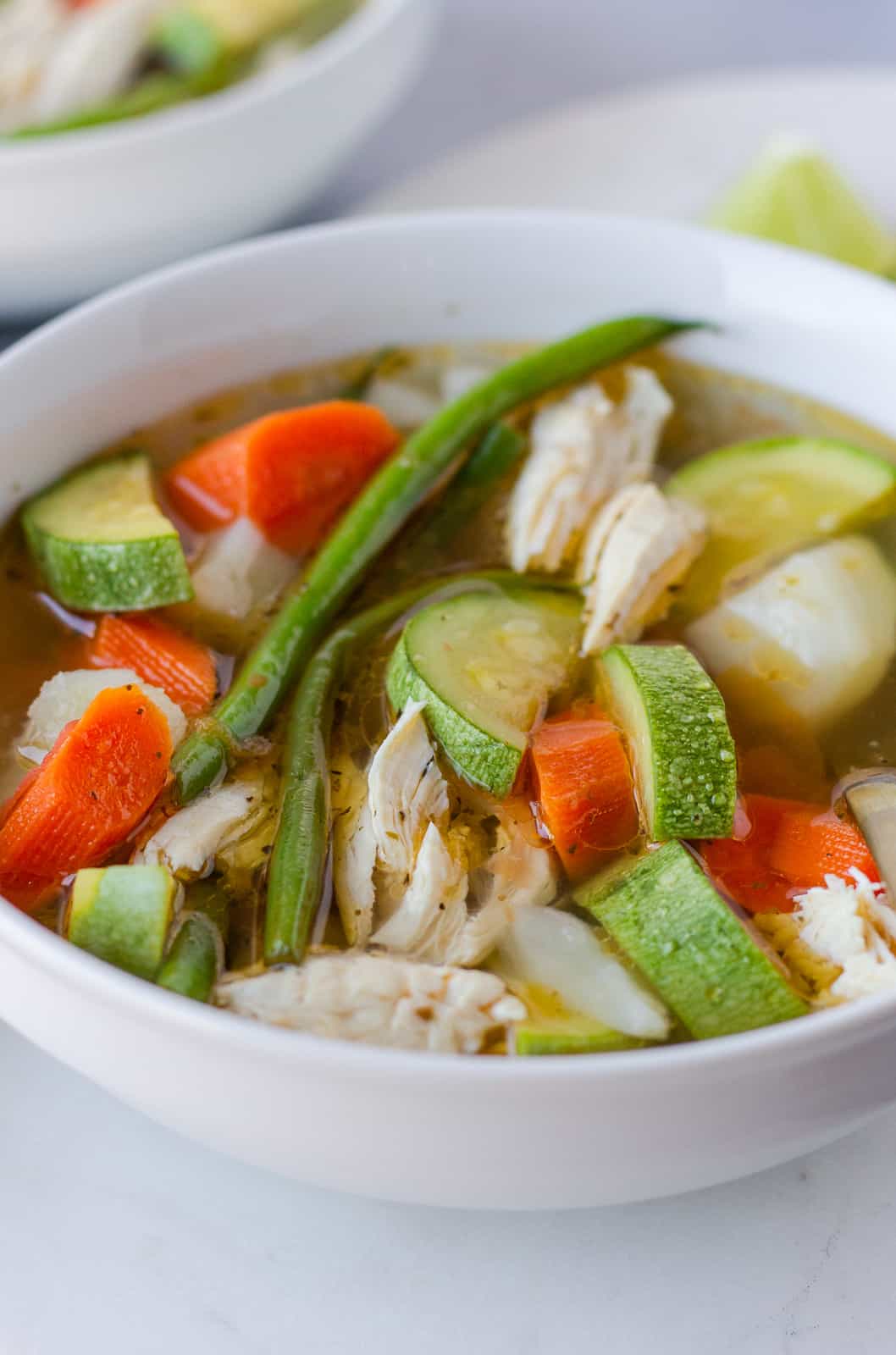 Up close view of soup with chicken and vegetable pieces.