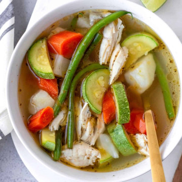 Up close view of caldo de pollo in a white bowl.