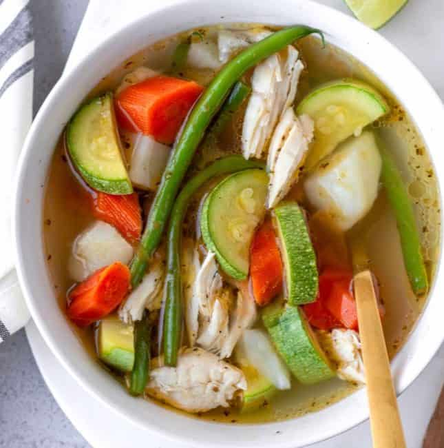 Up close view of caldo de pollo in a white bowl.