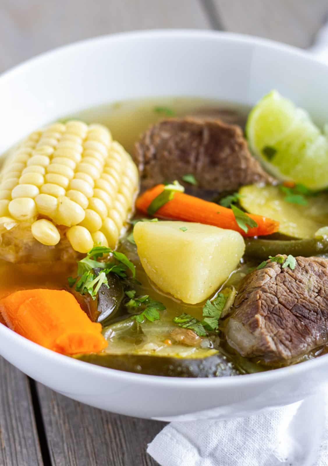 Corn on the cob, potato, beef, carrots, and zucchini, in a broth.