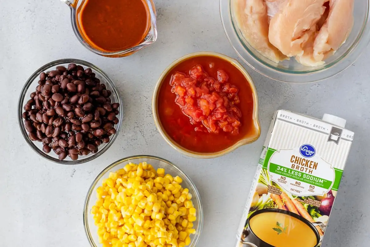 Black beans, corn, tomatoes, enchilada sauce, and chicken in individual bowls.