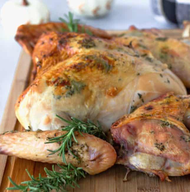 Up close view of cooked turkey on a cutting board with sprigs of rosemary.