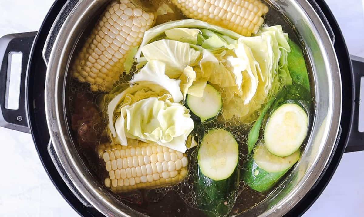 Corn, cabbage, and zucchini in the instant pot with water.