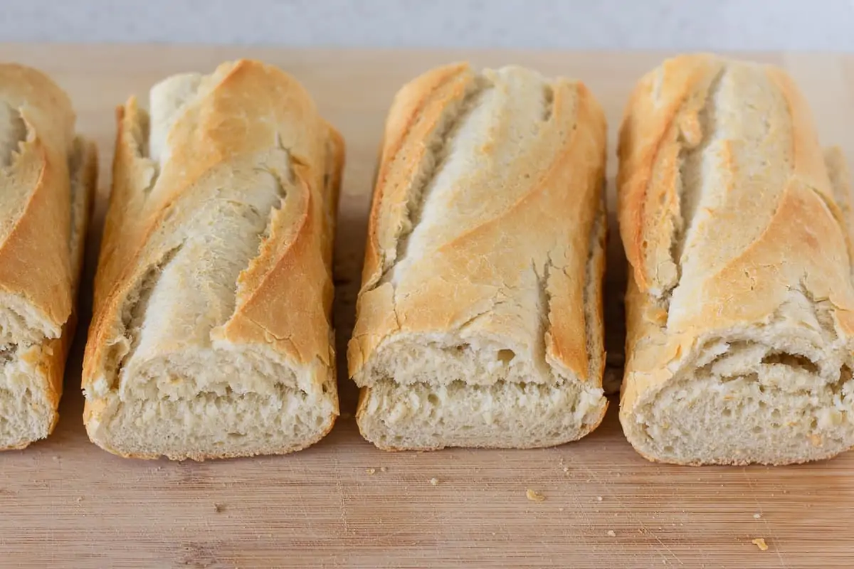Sliced baguettes on a wood cutting board.