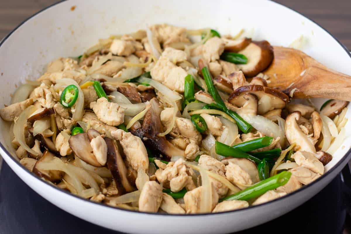 White skillet with cooked ginger chicken inside.