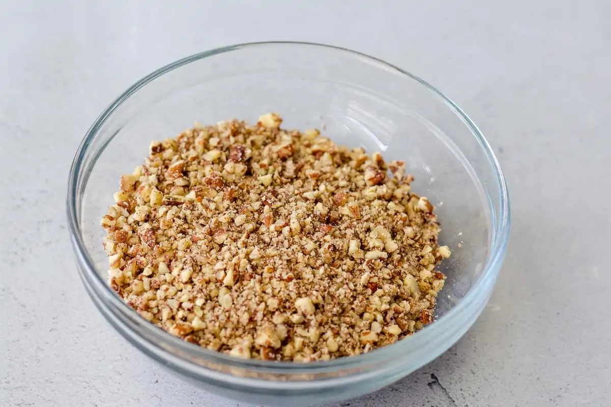 Crushed pecans in a glass bowl.
