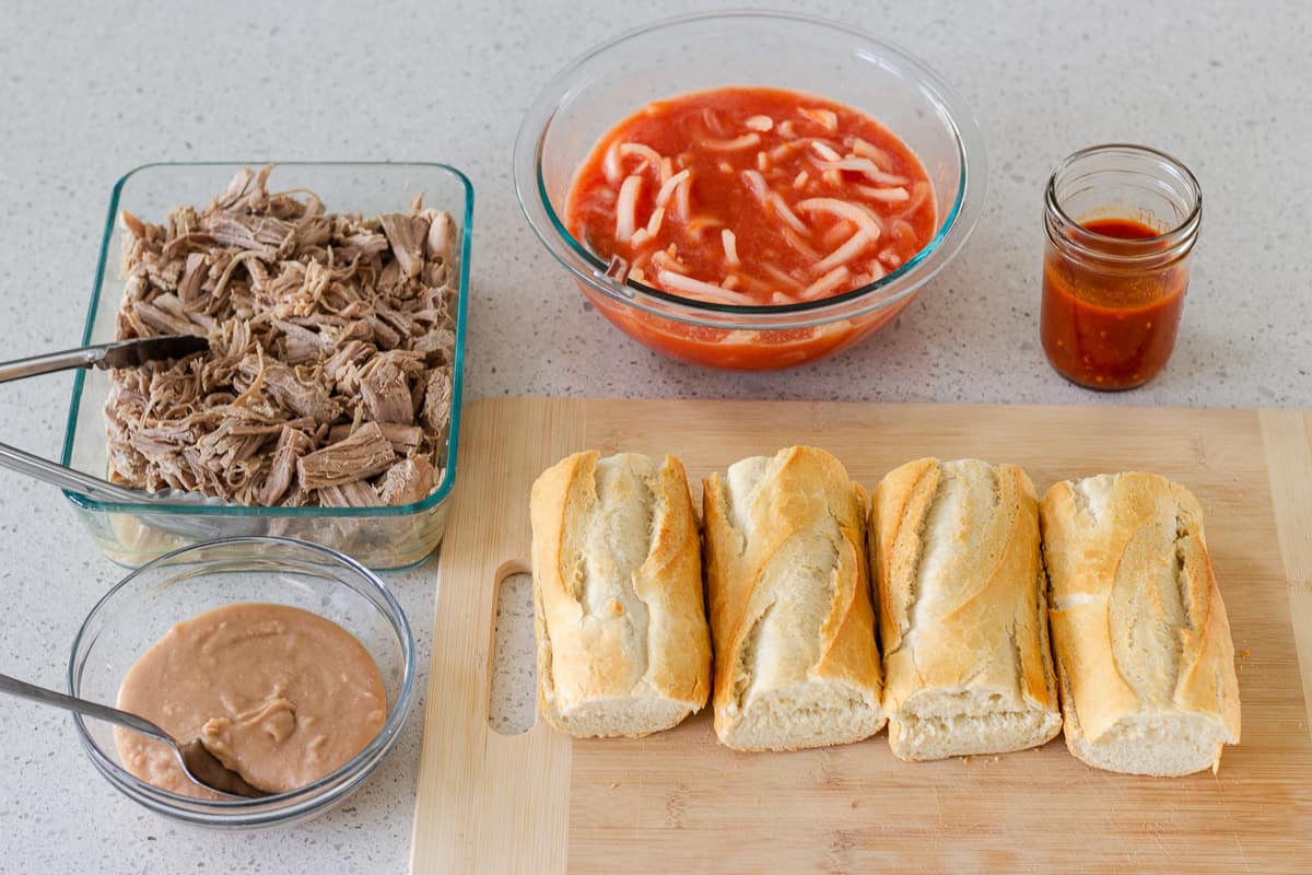 Shredded Pork, creamy beans, baguettes, tomato and onion sauce in a bowl.