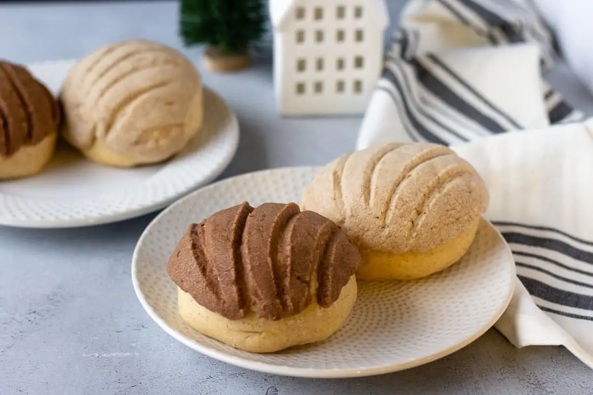 2 round plates with 2 chocolate and vanilla conchas on them.