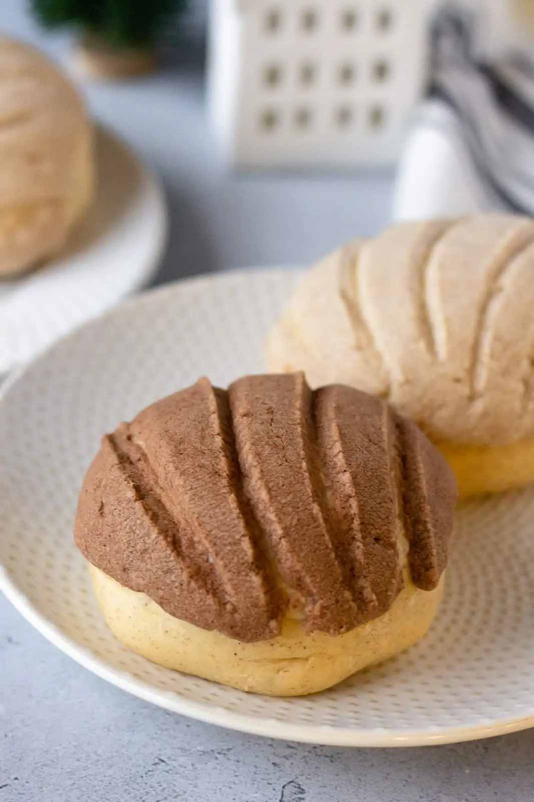 1 chocolate and 1 vanilla concha on a round plate.