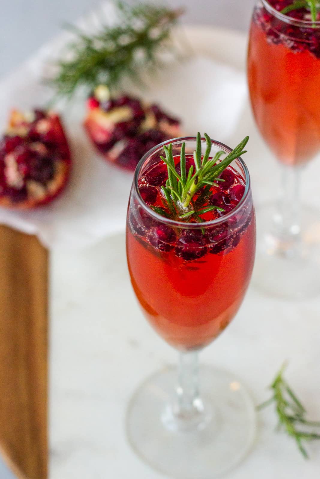 Up close view of cocktail with pomegranate seeds and rosemary.