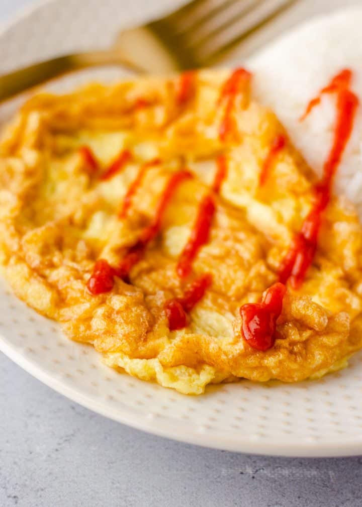 Up close view of Thai Omelet topped with siracha sauce.