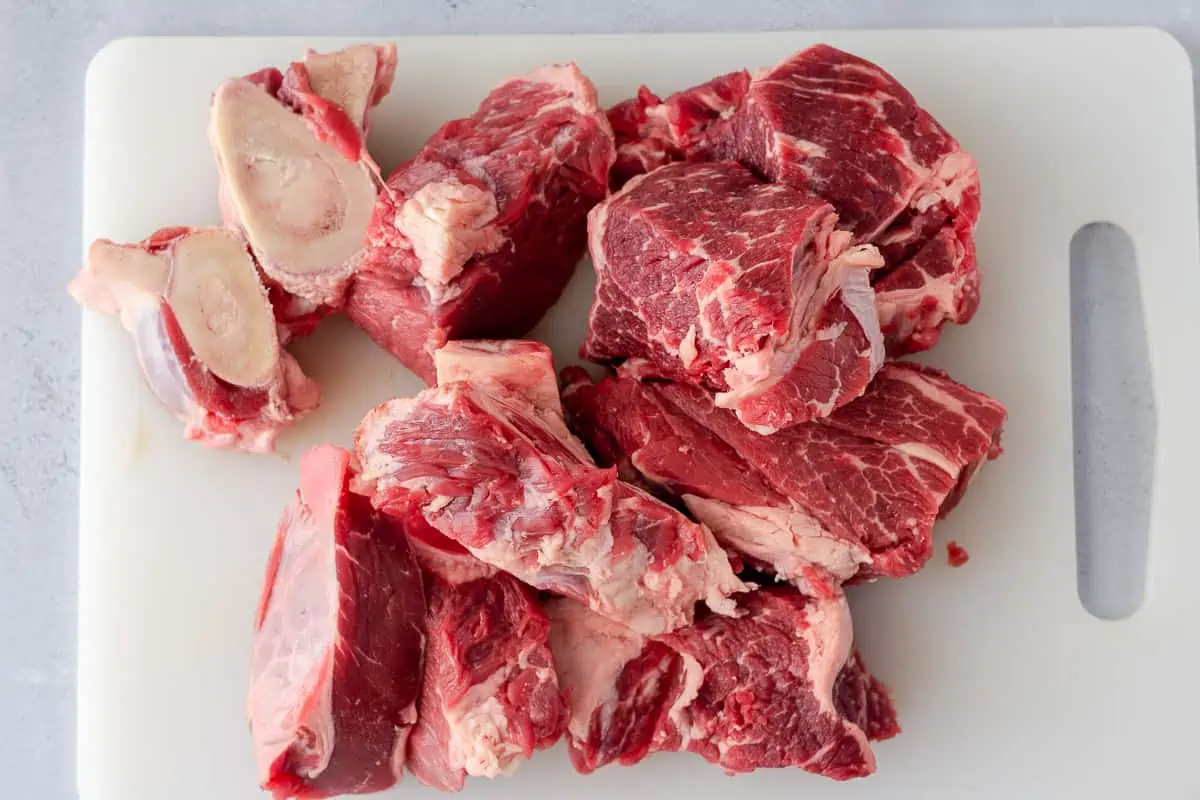Raw beef and bones on a cutting board.