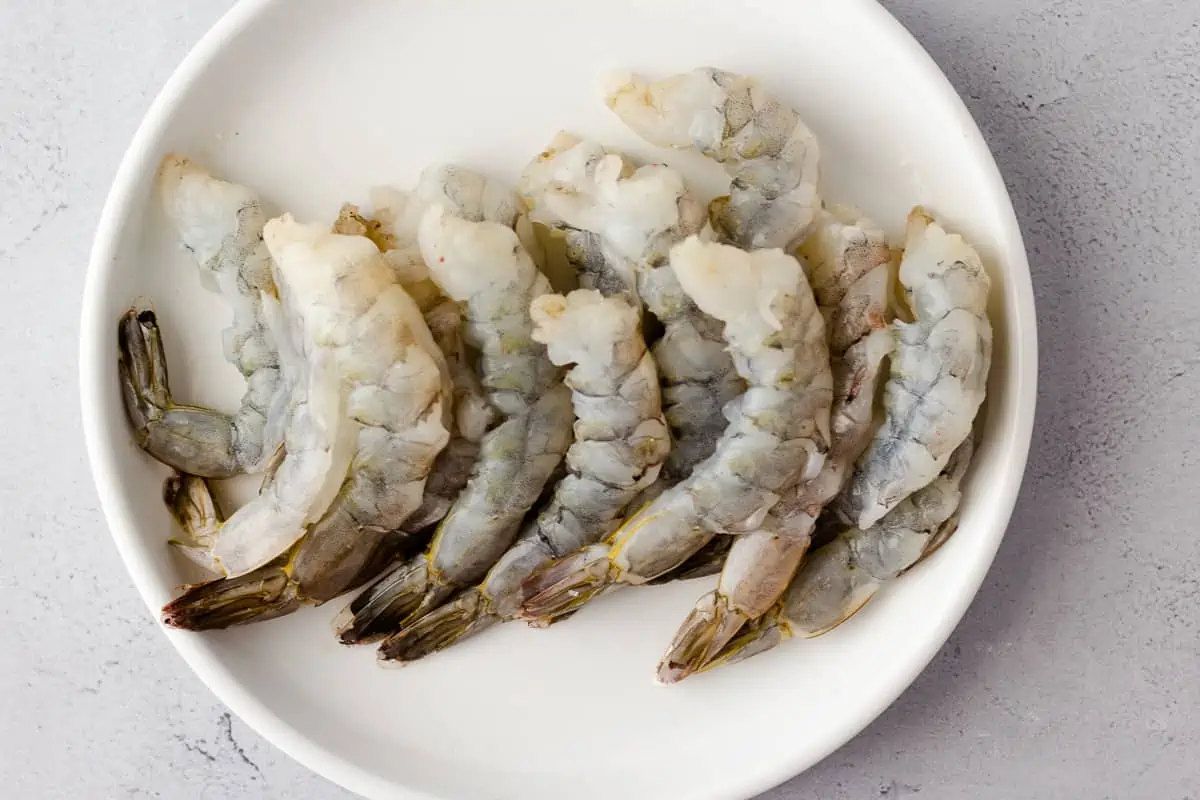 Raw shrimp on a white plate.