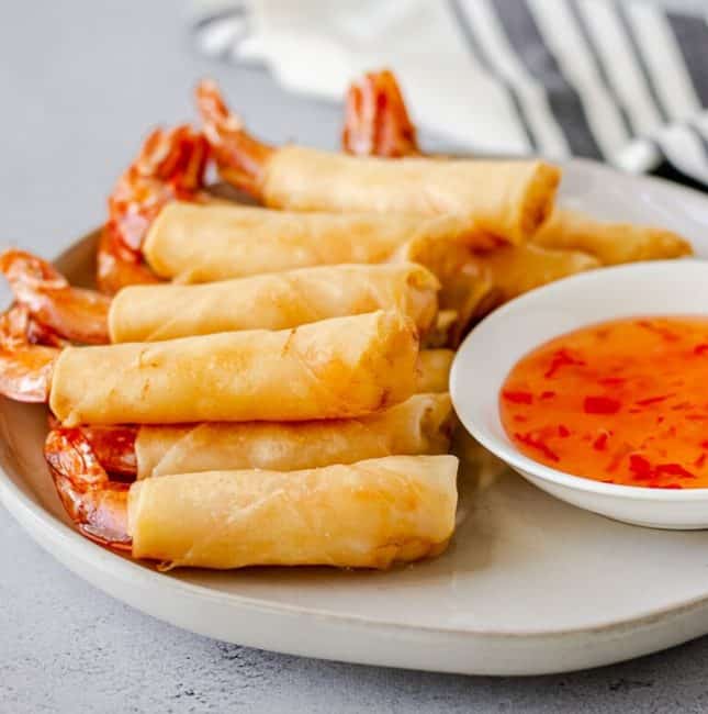 Up close view of fried shrimp rolls and sweet chili dipping sauce.