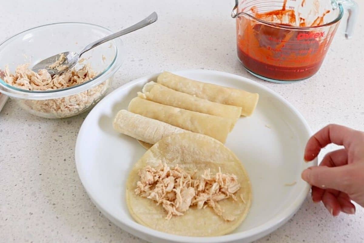Tortilla on a plate with shredded chicken in the middle.