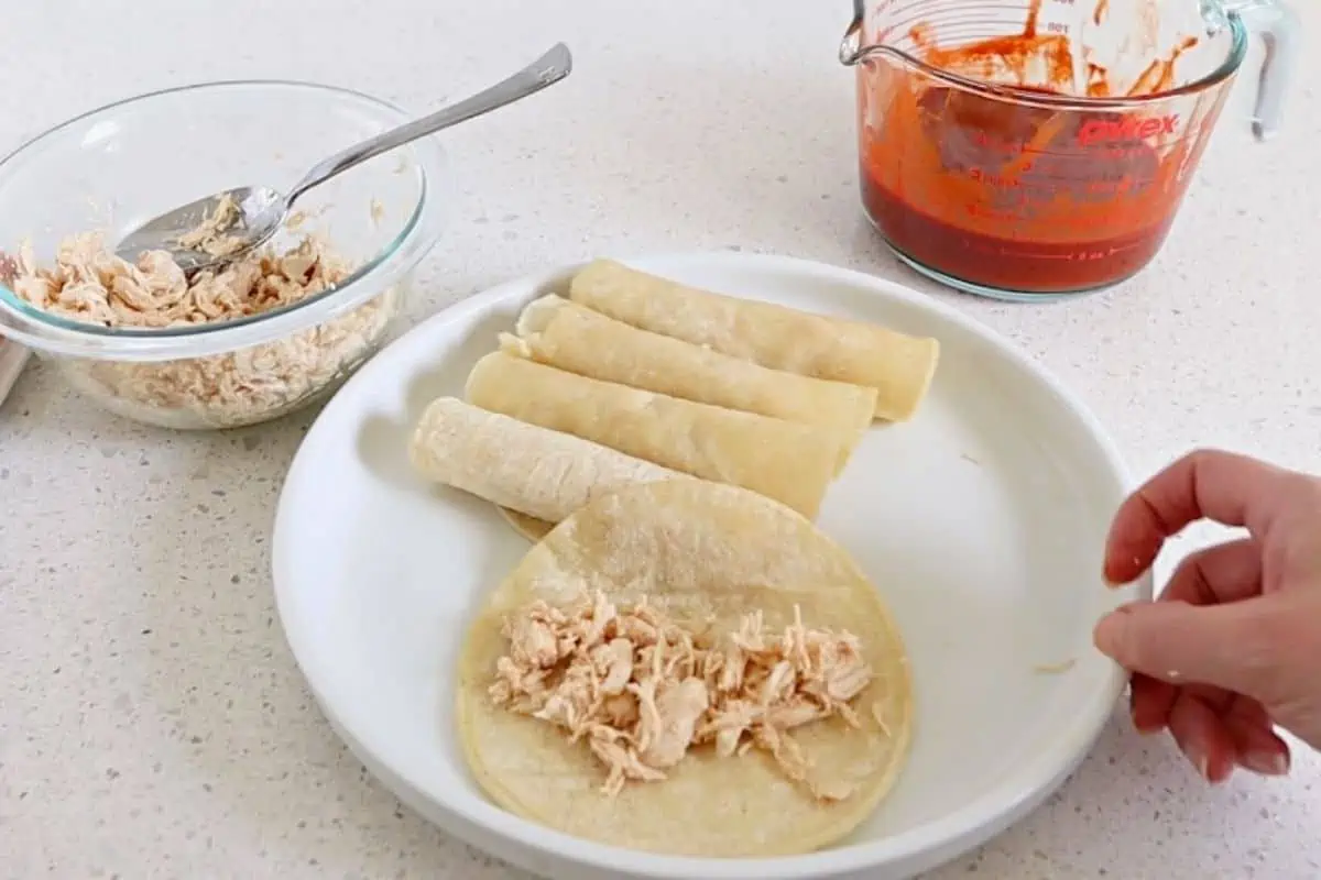 Tortilla on a plate with shredded chicken in the middle.